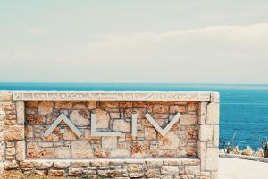 a sign on a wall with the ocean in the background at Aliv stone suites & spa in Agios Nikolaos