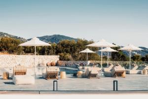 a group of chairs and umbrellas next to a pool at Aliv stone suites & spa in Agios Nikolaos