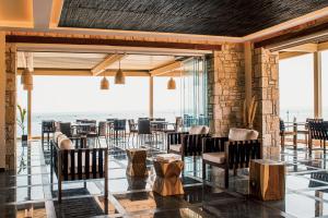 a dining room with tables and chairs and windows at Aliv stone suites & spa in Agios Nikolaos