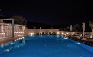 a large blue swimming pool at night with lights at Aliv stone suites & spa in Agios Nikolaos