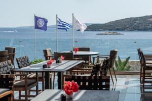 a restaurant with tables and flags in front of the ocean at Aliv stone suites & spa in Agios Nikolaos