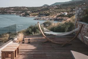 a hammock and a bench on a deck with the water at Aliv stone suites & spa in Agios Nikolaos