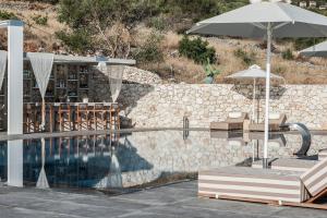 a swimming pool with two chairs and an umbrella at Aliv stone suites & spa in Agios Nikolaos