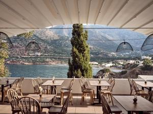 - un restaurant avec des tables et des chaises et une vue sur l'eau dans l'établissement Troulis Apart-Hotel, à Balíon