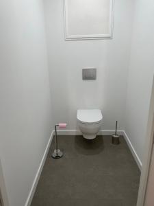 een badkamer met een wit toilet in een witte muur bij Gîte du centre equestre du val d'or in Fontaine-sur-Ay