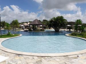 a large swimming pool in a resort with palm trees at ILOA RESIDENCE L202 in Barra de São Miguel