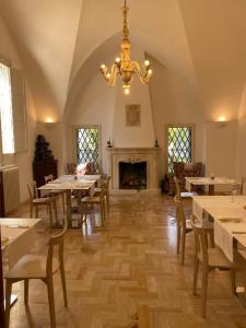a dining room with tables and a chandelier and a fireplace at Masseria Filippo de Raho - Agri Bio Relais in Convento