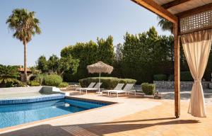 a pool with chairs and umbrellas in a yard at Agnes Villa, unrivalled living, By ThinkVilla in Pigi