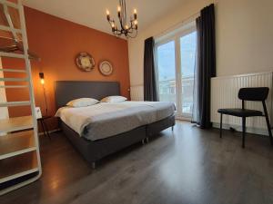 a bedroom with a bed and a chair and a window at Seapoint - Sea view in Zandvoort