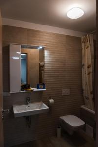 ein Badezimmer mit einem Waschbecken, einem WC und einem Spiegel in der Unterkunft Condmari VIP in Braşov