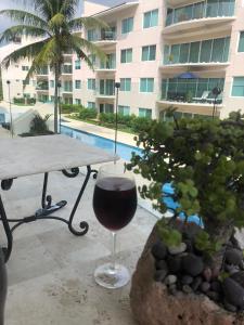ein Glas Wein auf einem Tisch vor einem Gebäude in der Unterkunft Hermoso y confortable departamento. in Ixtapa