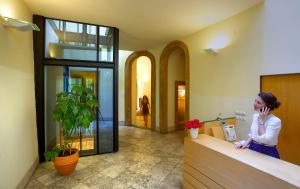 a woman standing at a counter talking on a cell phone at U Kapra Apartments in Prague