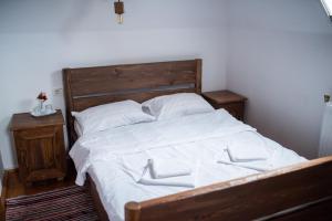 Bett mit weißer Bettwäsche und einem Kopfteil aus Holz in der Unterkunft Casa Strabunicului in Pîrteştii de Sus