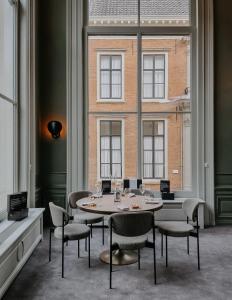 uma mesa e cadeiras num quarto com uma grande janela em The Nox Hotel em Utrecht