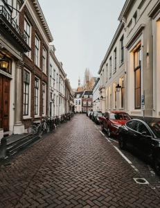 a cobblestone street with parked cars and buildings at The Nox Hotel in Utrecht