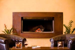 a living room with two leather chairs and a fireplace at Valis Resort Hotel in Volos