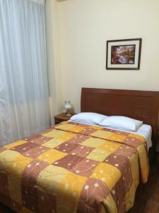 a bedroom with a bed with a quilt on it at Hotel Viña del Mar in Tacna