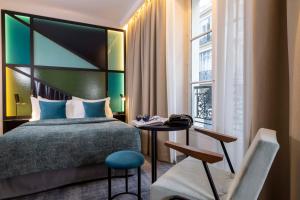 a bedroom with a bed and a table and a chair at Le 12 Hôtel in Paris