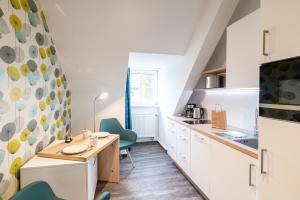 a kitchen with white cabinets and green chairs at Altes Wasserwerk, FW 7 in Zingst