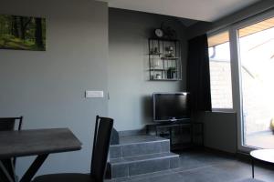a living room with stairs and a tv and a table at TERRASSES DE MALMEDY Triplex 224 LE CERF BLANC in Malmedy