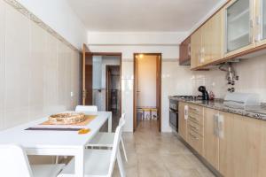 uma cozinha com um balcão branco e uma mesa branca em As Andorinhas em Portimão