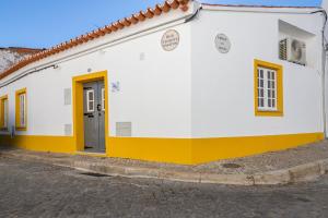 a white building with a yellow door on a street at Barrote Beja- Alojamento Local in Beja