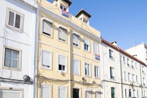 een hoog wit gebouw met witte ramen bij Charming 1 Bedroom Apartment w/ Terrace Near Belém in Lissabon