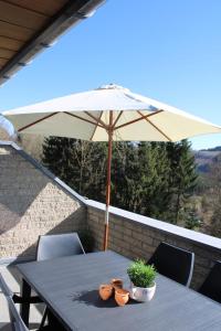 a table with an umbrella and two plants on a balcony at TERRASSES DE MALMEDY Triplex 224 LE CERF BLANC in Malmedy