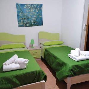 two beds in a room with green sheets and towels at B&B Il Girasole in Quattromiglio