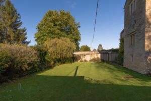 een grote tuin met een oud gebouw en bomen bij The Barracks in Northleach