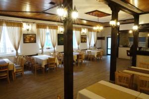 a dining room with tables and chairs and windows at Семеен хотел Орфей in Teshel
