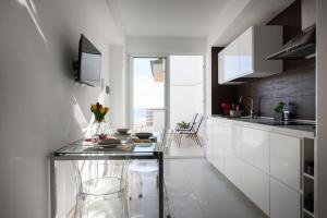 cocina con mesa de cristal y algunas sillas en MADAGÌ Beachfront Apartments, en Pozzallo