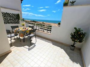 balcón con mesa y sillas y la playa en MADAGÌ Beachfront Apartments, en Pozzallo