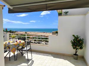 balcón con mesa, sillas y vistas al océano en MADAGÌ Beachfront Apartments, en Pozzallo