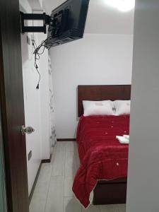 sypialnia z łóżkiem z czerwonym kocem i telewizorem w obiekcie PYMABET w mieście Huancavelica