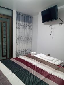 1 dormitorio con 1 cama y TV en la pared en PYMABET en Huancavelica