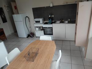 a kitchen with a wooden table and white appliances at F3, 3 pers - proche centre historique in Besse-et-Saint-Anastaise