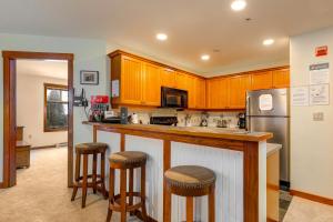 une cuisine avec des placards en bois et un comptoir avec des tabourets de bar dans l'établissement Eagle Springs East 302: Boxelder Suite, à Solitude