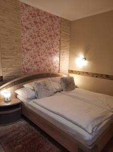 a bedroom with a large bed with a pink wall at Kék Lagúna Wellness Apartmanok in Egerszalók