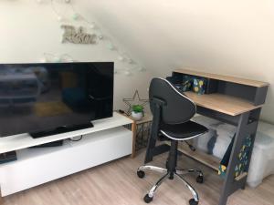 a desk and a chair in a room with a television at le Nid perché in Brou