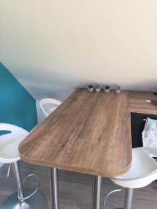 a wooden table in a room with white chairs at le Nid perché in Brou