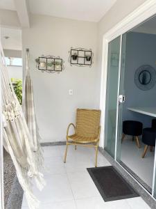 Habitación con silla y puerta de cristal en Residencial Rumo ao Mar - Bombinhas-SC, en Bombinhas