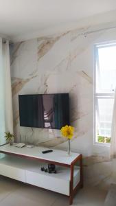 uma sala de estar com televisão e um vaso de flores sobre uma mesa em Flat Marimbá - Duplex em Porto de Galinhas
