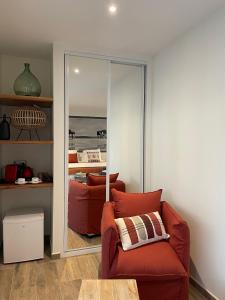 a living room with a red chair and a mirror at VILLA MADY Adultes Only in Andernos-les-Bains