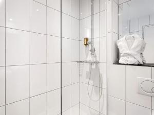 a white tiled bathroom with a shower with a hose at Schlosshotel Hellenstein in Heidenheim +35 photos