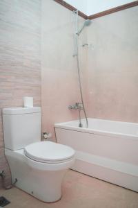 a bathroom with a white toilet and a bath tub at Tarshish Villa - Colombo in Colombo