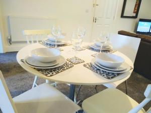 a white table with plates and wine glasses on it at Modern comfy 2-Bedroom flat in St Helens in Saint Helens