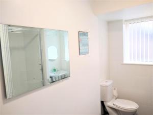 a white bathroom with a toilet and a mirror at Modern comfy 2-Bedroom flat in St Helens in Saint Helens