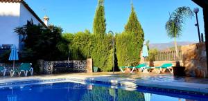 a swimming pool with chairs and tables and trees at Hotel Rural Los Jarales in Istán