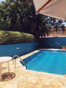 una pequeña piscina con mesa y sombrilla en Pousada Canto Bella Terra en Ilhabela